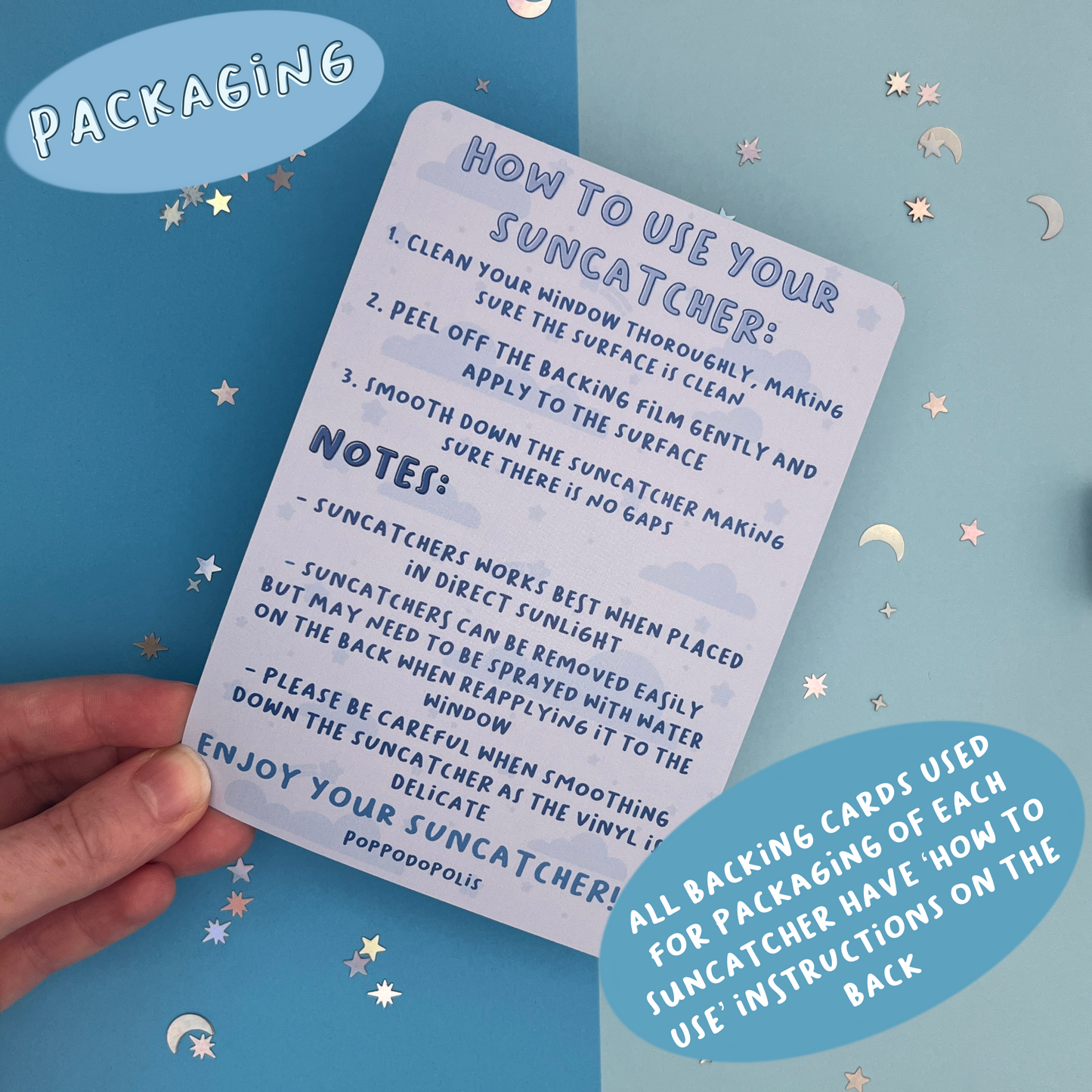 Hand holding a card with 'How to Use Your Suncatcher' instructions on a blue background with star and moon decorations.